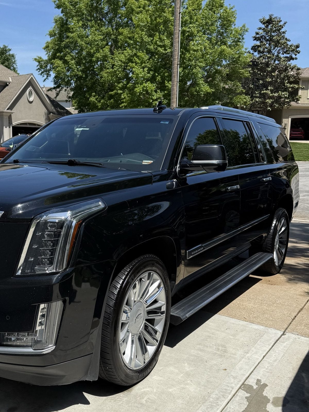 Freshly detailed black Cadillac Escalade in a Raymore driveway